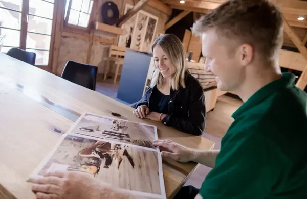 Zwei Personen besprechen Holzmöbel-Designs in einem modernen, hellen Innenraum.