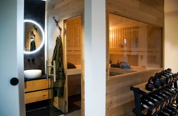 Moderner Wellnessbereich mit Sauna, Fitnessgeräten und stilvollem Badezimmer im Holzdesign.
