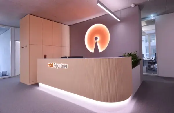 Modernes Büro mit Empfangstresen, leuchtendem Wandlogo und stilvoller Innenarchitektur.