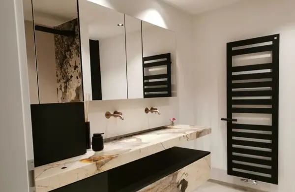 Modernes Badezimmer mit Naturstein-Waschtisch, schwarzen Armaturen und Designheizkörper.