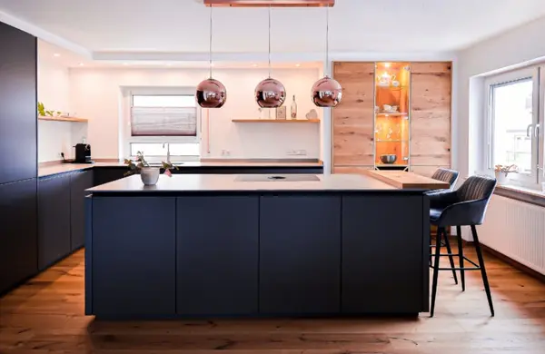 Moderne offene Küche mit Kochinsel, Hängelampen, Holzfußboden und großen Fenstern.