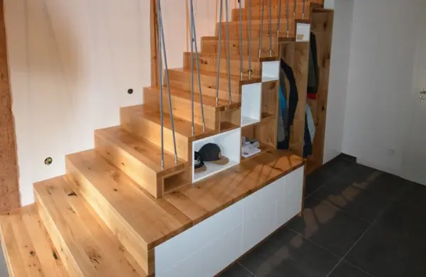 Moderne Holztreppe mit integriertem Stauraum und offenen Regalfächern im Eingangsbereich.