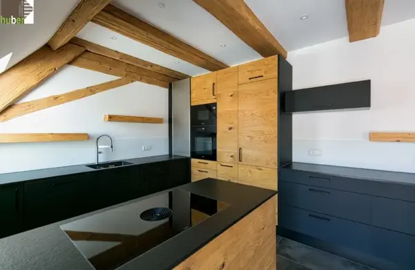 Moderne Einbauküche mit Holzfronten, schwarzen Elementen und offenliegenden Holzbalken.